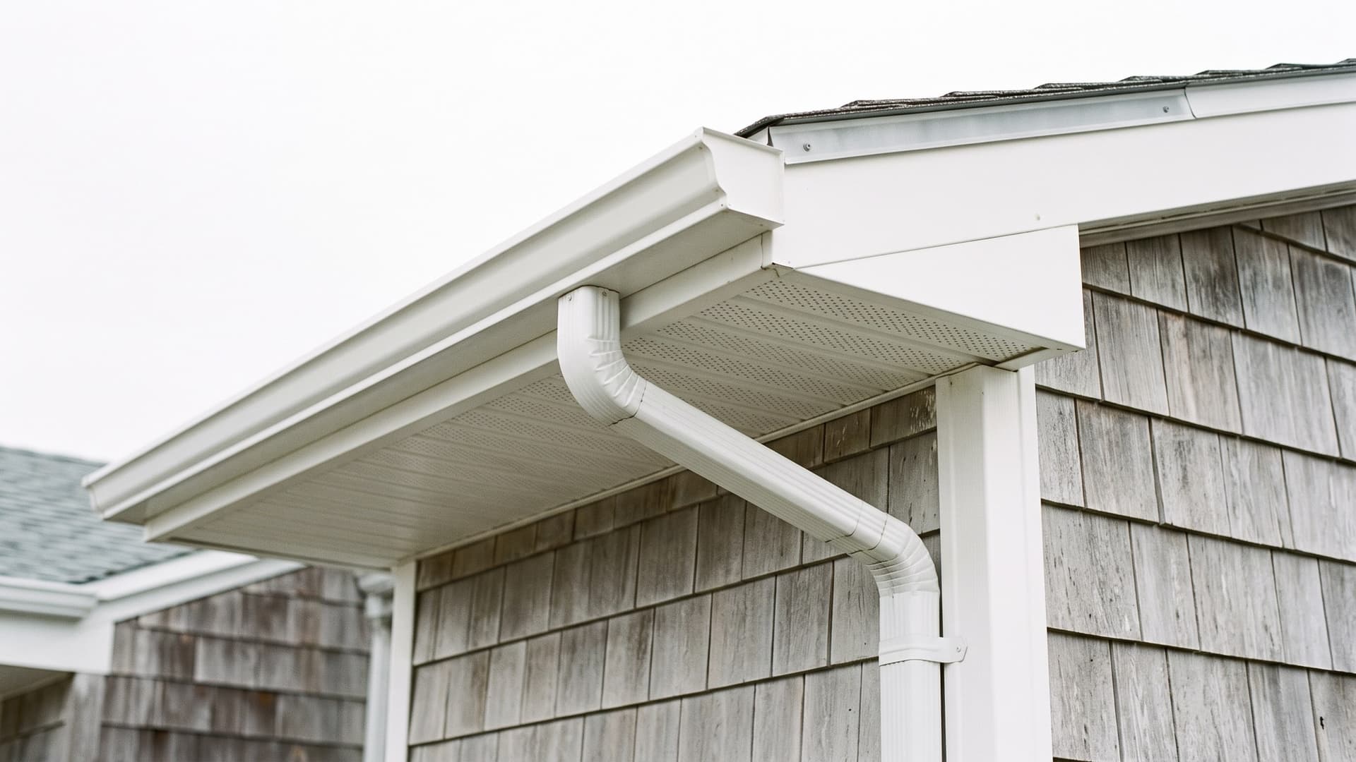 Roofline eave on an Ocean County NJ home showing vinyl soffit, fascia board and an aluminum K-style gutter with drip edge above.
